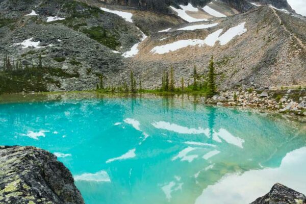 A turquoise pool of water frames a spectacular mountain in Tonquin Valley photographed by Nick Fitzhardinge.