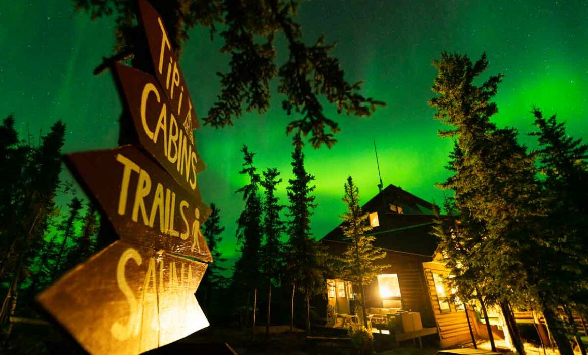 A fly in backcountry lodge in the Northwest Territories wilderness with the aurora above.