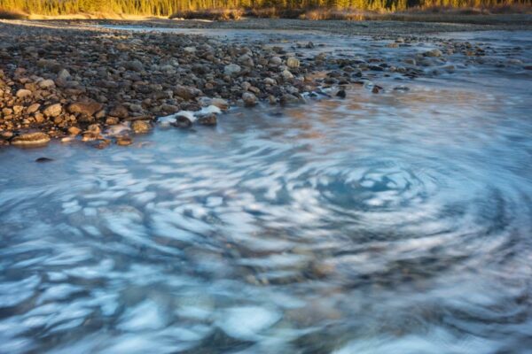 Sunrise striking Castle Mountain and foam swirling in the Bow River photographed by Nick Fitzhardinge.