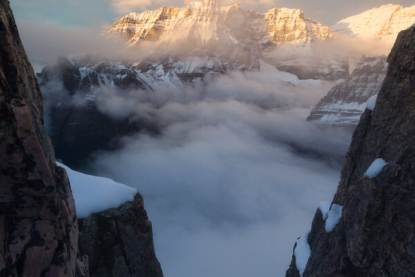 Sunset at the summit of a snowy Mt Schaffer high above a fog covered Lake O'Hara photographed by Nick Fitzhardinge.