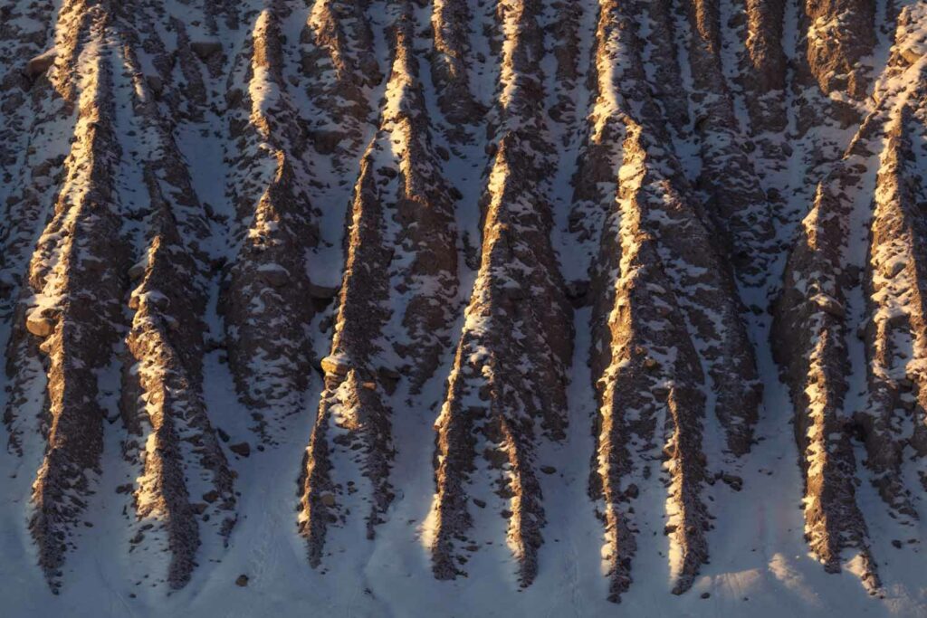 “LIGHT RUNNELS” Erosion along a road cut in the Canadian Rockies is highlighted by fresh snow and light photographed by Nick Fitzhardinge.