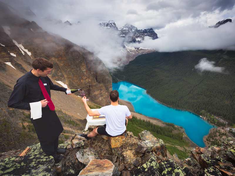 Canadian landscape photographer Nick Fitzhardinge serving wine and cheese on the top of the Tower of Babel above Moraine Lake in Banff National Park.