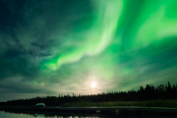 A reflected moon halo being wrapped by a swirling aurora at Vee Lake near Yellowknife during a northern lights photo tour offered by Nick Fitzhardinge.