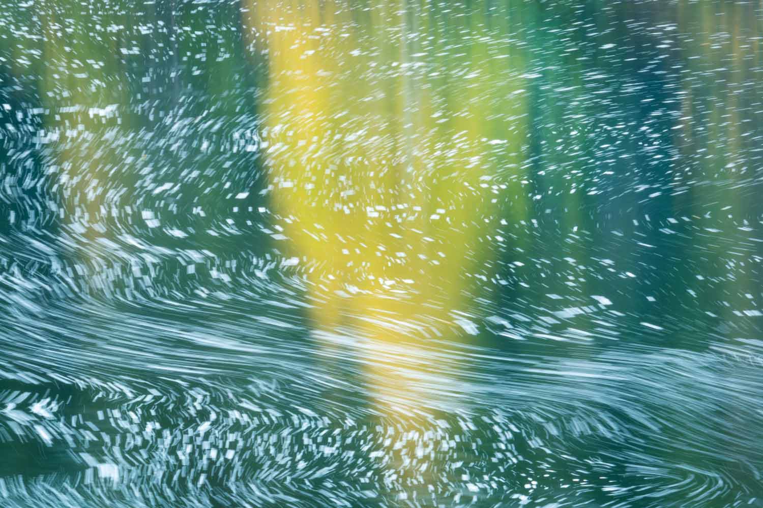 Fall colours and swirling foam reflected in the water near the base of Cameron Falls in the Northwest Territories photographed by Nick FItzhardinge.